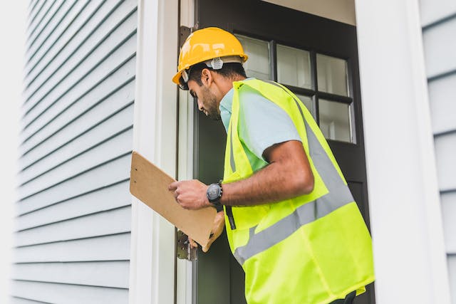 person-in-yellow-safety-reflective-vest-with-hard-hat-doing-house-inspection