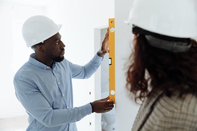 two-people-in-hardhats-using-a-level-to-measure-a-wall