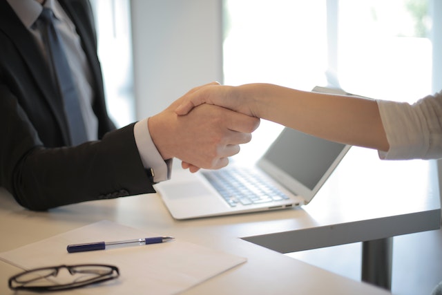 two-people-shaking-hands-over-desk