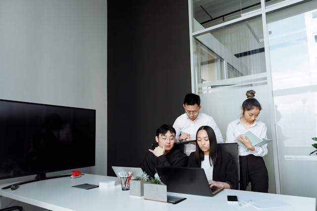 a-group-of-four-professionals-collaborating-in-a-modern-office-with-laptops-and-documents