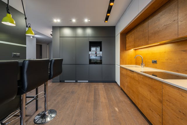 a-modern-kitchen-with-wooden-cabinets-black-barstools-and-sleek-lighting