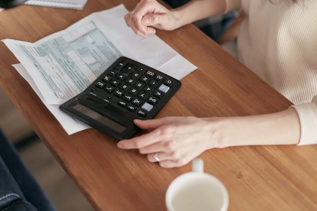 a-person-using-a-calculator-while-reviewing-financial-documents-on-a-wooden-table