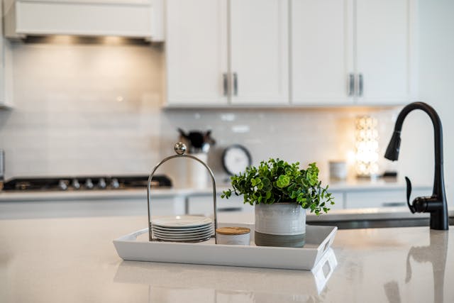 a-modern-kitchen-counter-with-a-tray-holding-plates-a-plant-and-decor-alongside-a-black-faucet