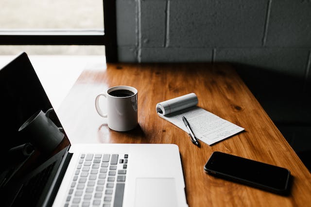 computer-phone-coffee-and-notepad-on-wooden-table