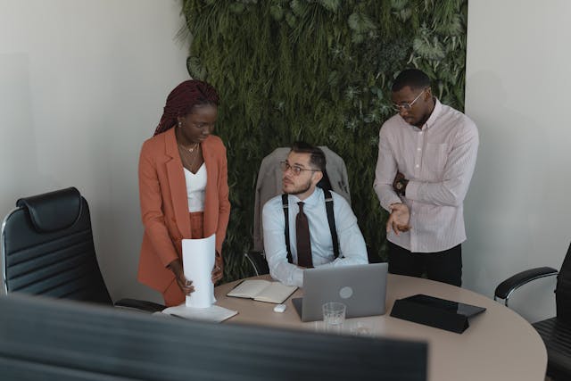 three-professionals-discussing-work-in-a-modern-office-with-a-green-wall-in-the-background