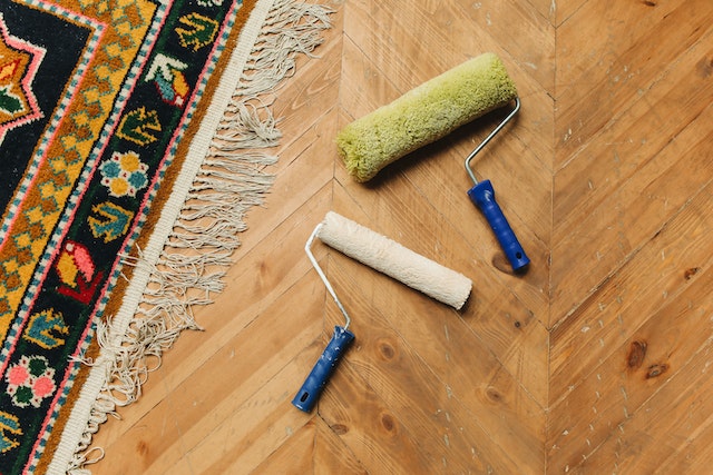 two-paint-rollers-on-the-ground-next-to-a-rug