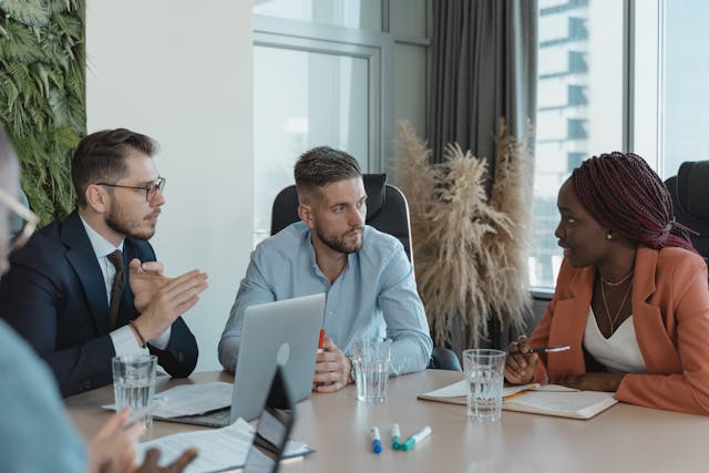 a-group-of-people-sitting-around-a-conference-table