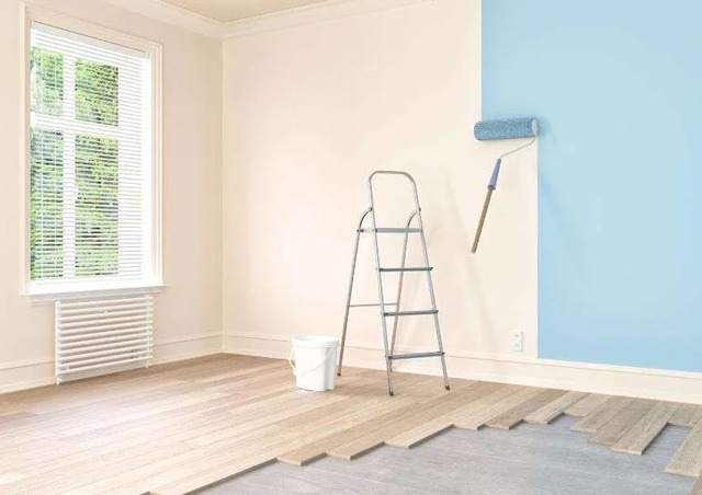 a-lander-and-paint-roller-in-a-white-room-with-the-roller-painting-the-walls-blue