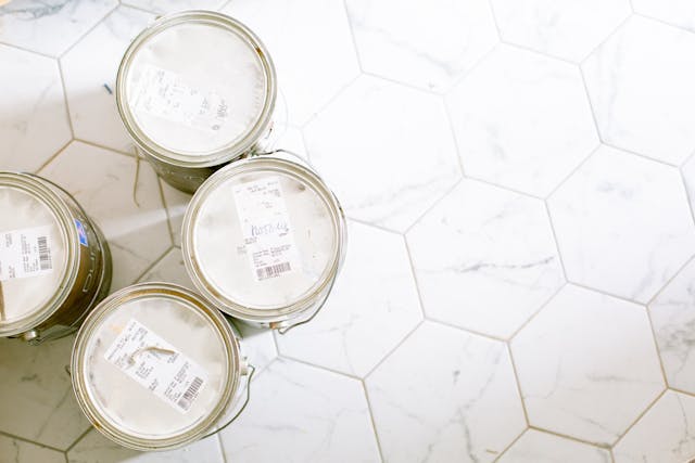 four-cans-of-paint-placed-on-a-white-hexagonal-tiled-floor-viewed-from-above