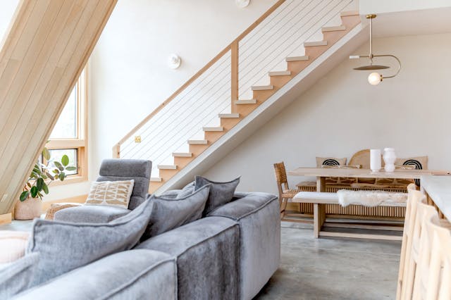 modern-living-and-dining-area-with-a-cozy-gray-sofa-wooden-staircase-and-a-minimalist-dining-table-under-the-stairs