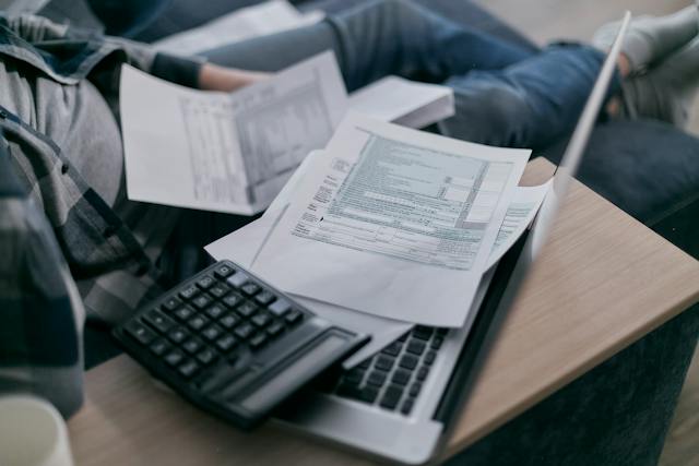 person-sitting-down-with-a-laptop-calculator-and-financial-documents