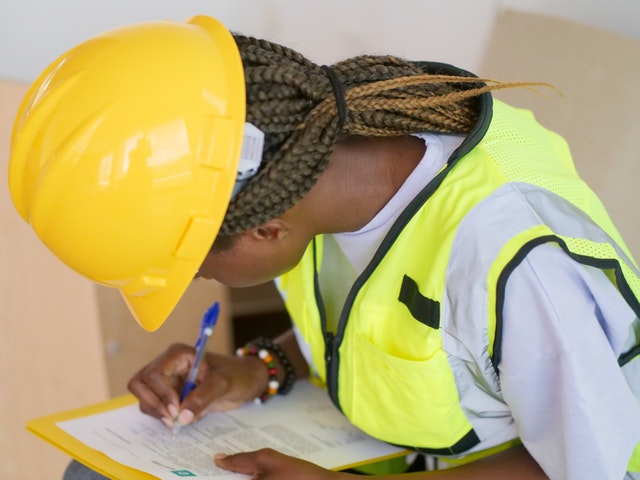 a-person-in-yellow-hard-hat-filling-out-an-maintenance-report