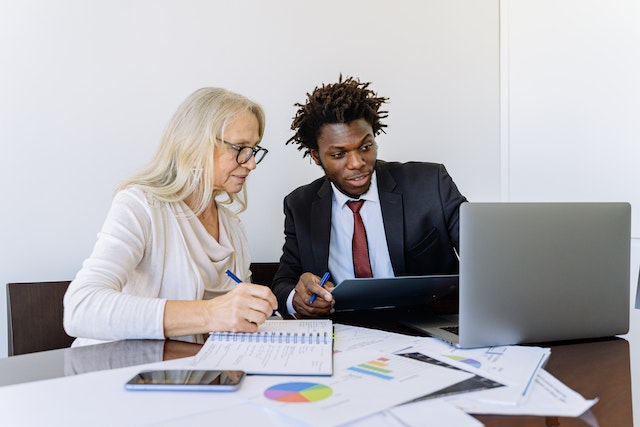 a-property-manager-in-a-black-suit-going-over-stats-with-someone-in-a-white-shirt