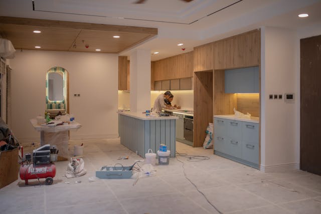 modern-kitchen-under-renovation-with-tools-and-materials-scattered-around-and-a-person-working-at-the-stove