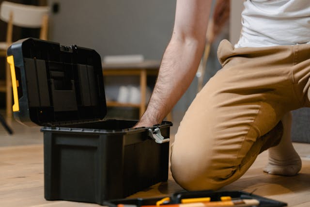 person-kneeling-on-the-floor-reaching-into-an-open-black-toolbox