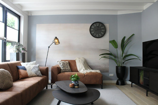 modern-living-room-with-brown-sofas-decorative-pillows-a-wall-clock-and-indoor-plants