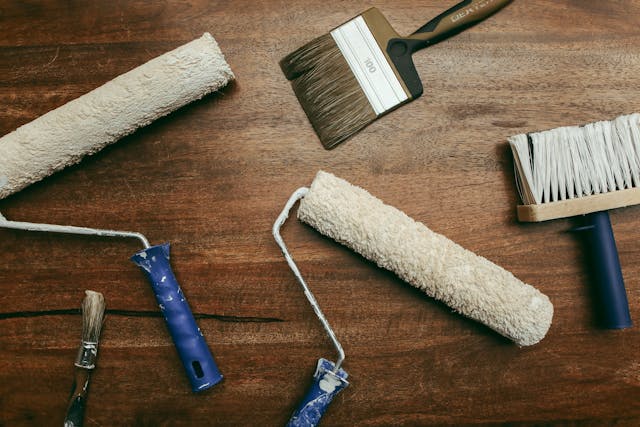 various-paint-rollers-and-brushes-laid-out-on-a-wooden-surface