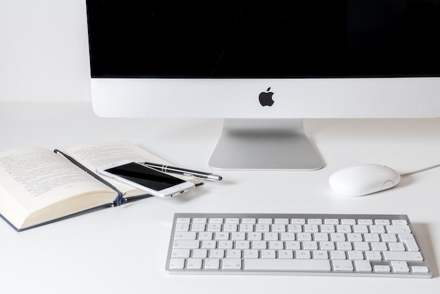 computer desk top, notepad and phone on a white desk