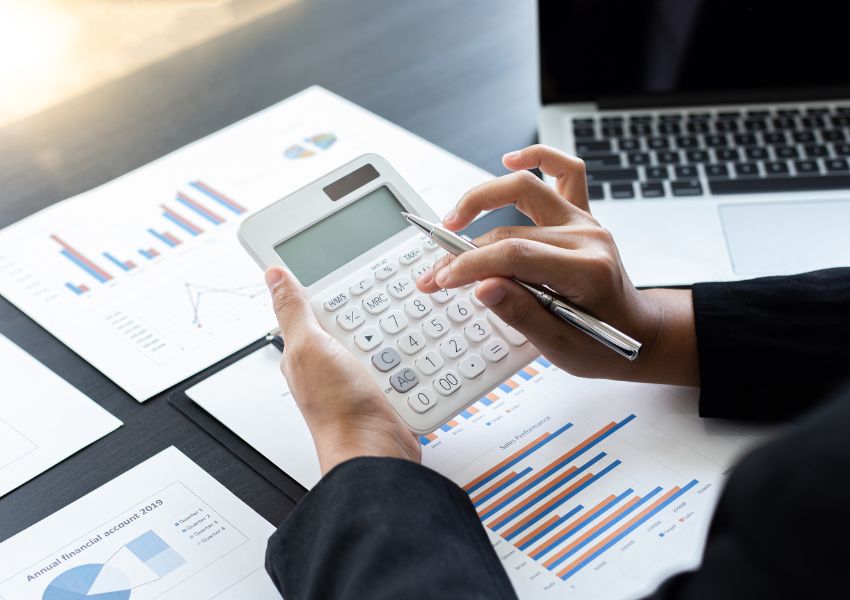 person holding a pen and calculator while looking over graphs