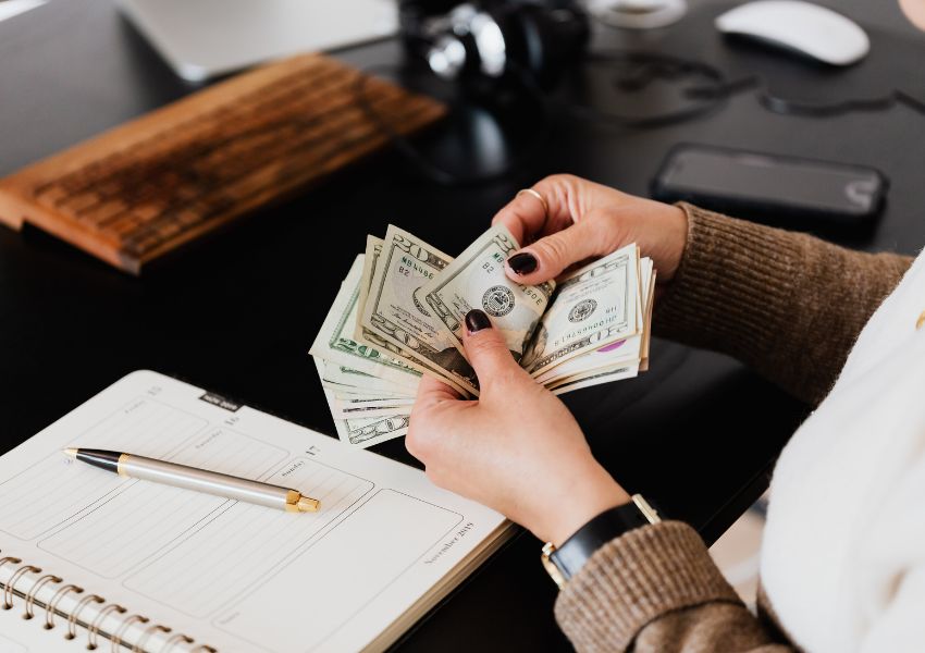 person sitting at their desk counting cash and noting down