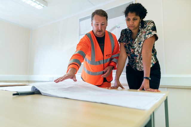 a contractor and property owner looking over a home's blueprints before making repairs