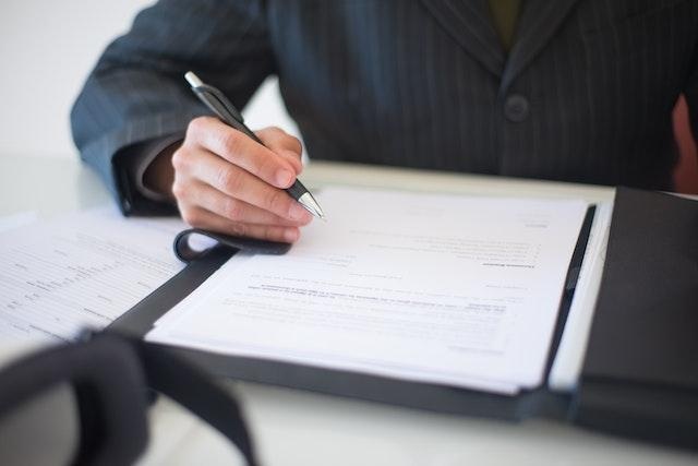 a-man-in-a-suit-signing-a-document-with-a-pen-on-a-clipboard