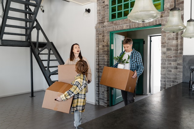 a-small-family-carrying-boxes-into-an-open-floor-plan