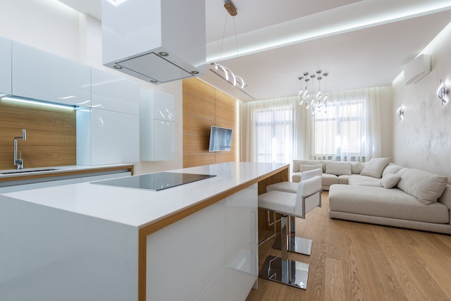 an open-concept white kitchen and living room with light wood flooring