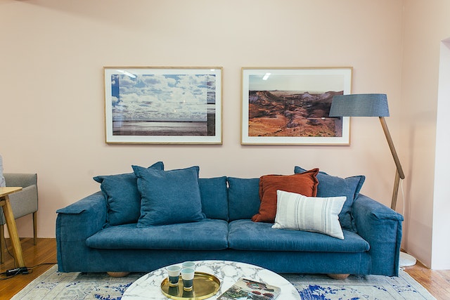 blue living room couch with two landscape photos above it