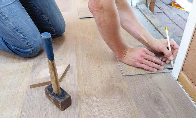 contractor making marks on some floorboards so they fit into a corner