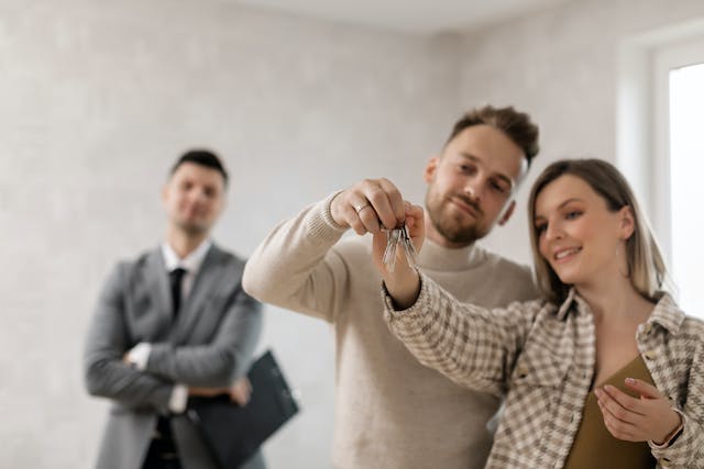 couple-looking-at-new-house-keys-while-property-manager-looks-on