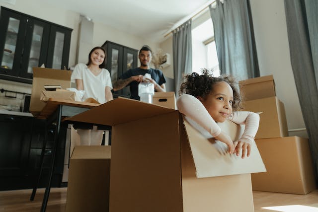 family-moving-in-to-house-with-little-child-playing-in-moving-boxes