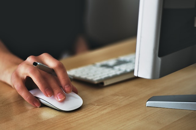 hand holding a pen white using a computer mouse