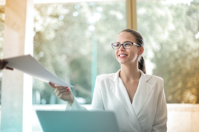 person being passes a piece of paper as they sit at their desk