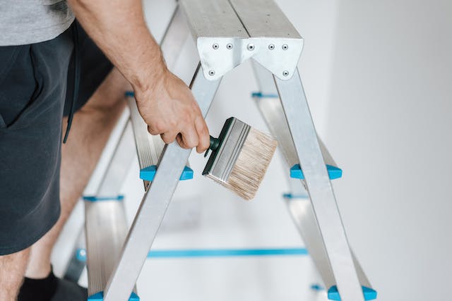 person-climbing-on-a-ladder-with-a-paint-brush