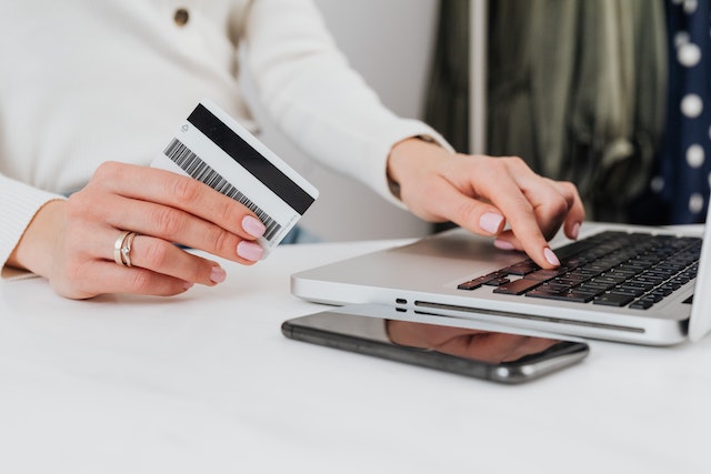 person holding a credit hard while looking a their laptop to making an online payment