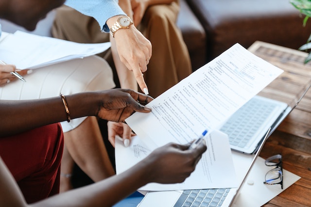 person holding a document while someone points to a specific paragraph