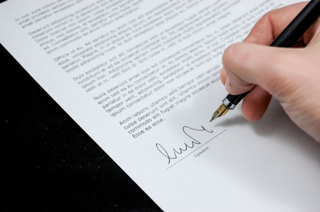 person holding a fountain pen to sign their name on a contract