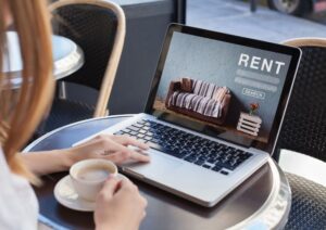 person looking at a rental listing on their laptop while they hold a cup of coffee