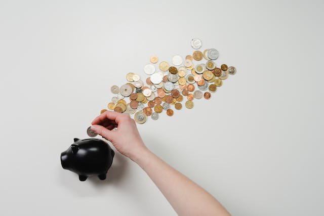 person-putting-coins-in-a-piggy-bank-with-coins-around it