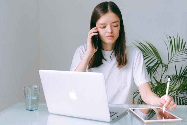 person-with-a-laptop-in-front-of-them-talking-on-the-phone-writing-notes-on-an-ipad-holding-an-apple-pencil