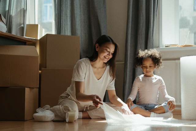 mom and daughter sitting on the floor surrounded by moving boxes