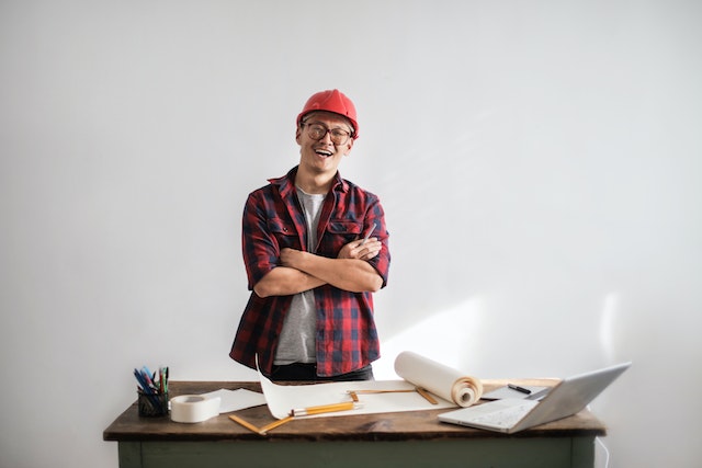 property maintenance person wear a hard hat and looking over floor plans