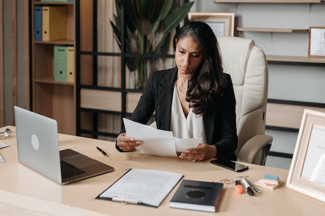 property manager sitting at their desk looking over documents with their laptop open in front of them