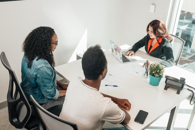 property manager speak with two tenants at their sit at a white desk