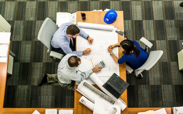 three contractors looking over a homes blue prints