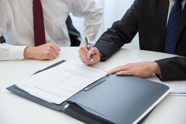 two business professionals in suits looking over a contract together