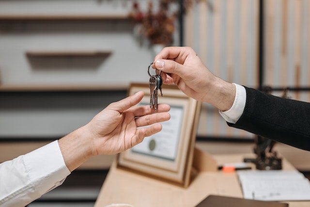 two-people-exchanging-keys-at-a-desk