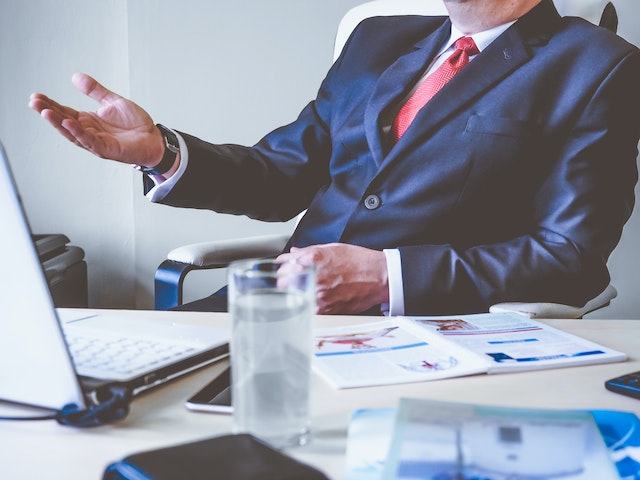 property managers in a blue suit and red tie in front of their desk that’s covered in documents