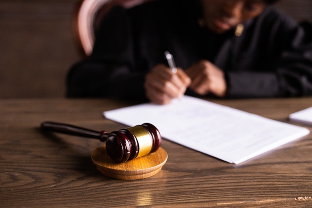 judge writing notes on a piece of paper with the gavel in foreground of the image